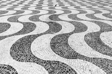 Wavy pattern of the beautifully paved Pedro IV square in Lisbon, Portugal - obrazy, fototapety, plakaty