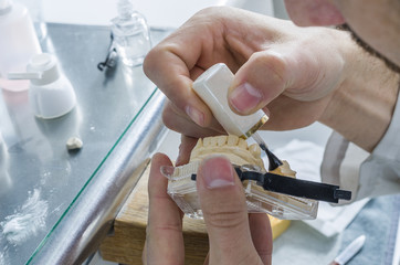 Dental technician applying ceramics to teeth in the dental model