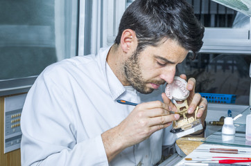 Dental technician applying ceramics to teeth in the dental model