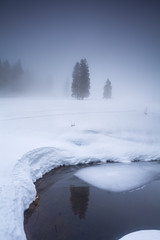 lake in mountains during foggy winter morning