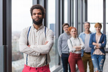 Corporate portrait of young black hipster businessman with his colleagues in background.