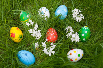 Multicolored eggs in a nest on green grass background. Easter decoration