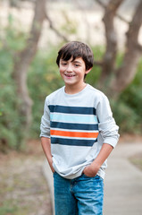 Fototapeta premium Smiling Cute young boy standing on sidewalk looking at camera