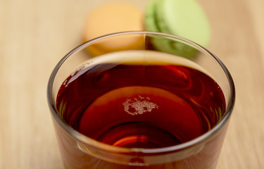 Glass cup of black tea and colorful macarons