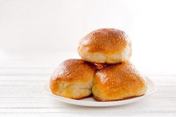 Three rosy appetizing buns on a plate on a white background natural