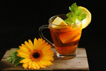 Lemon fruit tea infusion on a wooden surface with a yellow flower