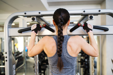 Fototapeta na wymiar Woman in gym flexing back muscles on cable machine