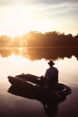 Man in fishing boat on lake - 103190485