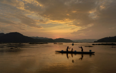 Fototapeta premium two fisherman throwing nets during on sunset in Meakhong river Thai-Loas