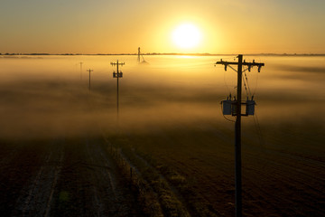 Telephone poles and farm ranch rural countryside silo on a foggy misty morning at sunrise or sunset