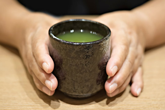 Woman hand holding a cup of Green tea