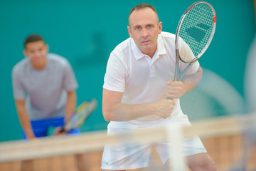 Men playing doubles tennis