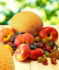 image of different fruits on wooden table on green background