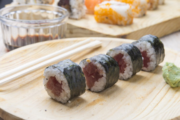 Different Sushi rolls,wasabi and ginger on a plate on wooden bac
