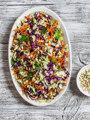 Fresh vegetable salad with red cabbage, carrots, sweet peppers, herbs and seeds. Healthy vegetarian food. On light  wooden rustic background