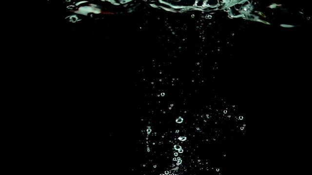 One large strawberry being dropped into water in super slow motion (500 frames per second) against a black background.
