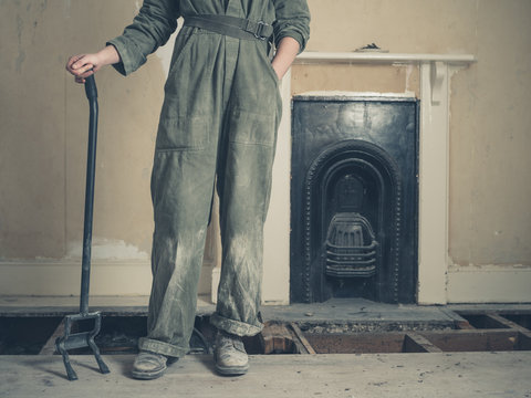 Woman with crowbar standing by fireplace