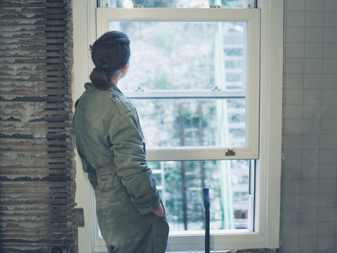 Woman in boiler suit looking out the window