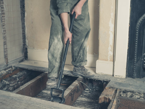 Young woman in boiler suit removing floor boards