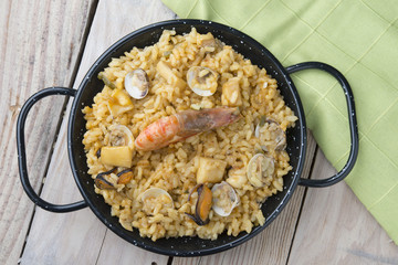 Vegetable paella with seafood on a wooden background