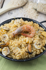 Vegetable paella with seafood on a wooden background