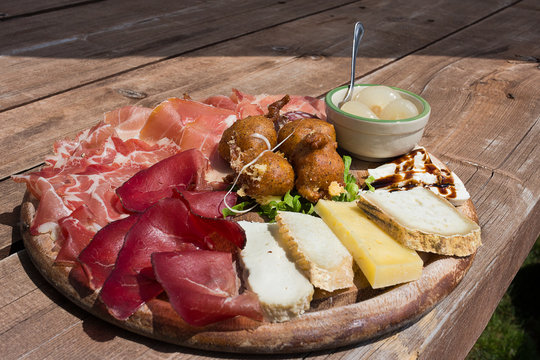Valtellina - Typical culinary delights served at the alpine huts. The platter after trekking: speck,cheese,sciatt (buckwheat cheese fritters),ham, onion. Italy

