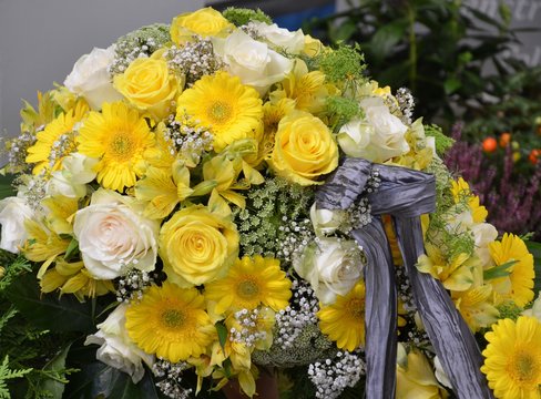 Gelbe und wei&szlig;e Rosen, Gerbera und Lilien im Blumenstrau&szlig; mit Trauerschleife zur Beerdigung
