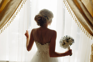 beautiful bride in a wedding dress, by window.