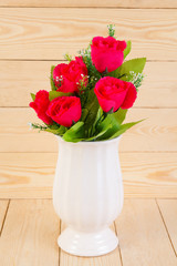 Red roses in pot on wood texture for background.