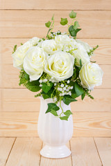 White roses in pot on wood texture for background.