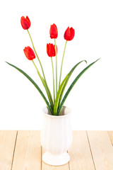 Red tulips in pot on wood texture isolated on white background