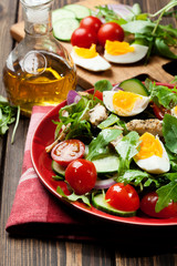 Fresh salad with chicken, tomatoes, eggs and arugula on plate