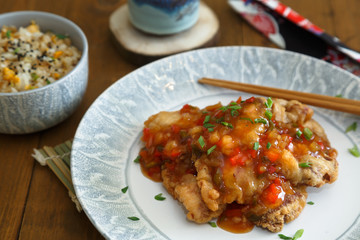 Sweet and sour pork and rice on plate with chopsticks, Chenese cuisine