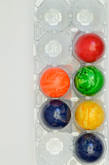 Bunte Eier / bunte Ostereier in einem Eierkarton, Plastik, Nahaufnahme, Makro, isoliert, weißer Hintergrund, Querformat, vertikal


