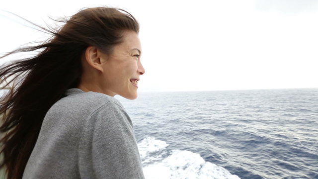 Cruise ship woman on boat in happy smiling looking at camera and looking away. Young woman traveling on vacation travel sailing on open sea ocean. Mixed race Asian Caucasian woman.