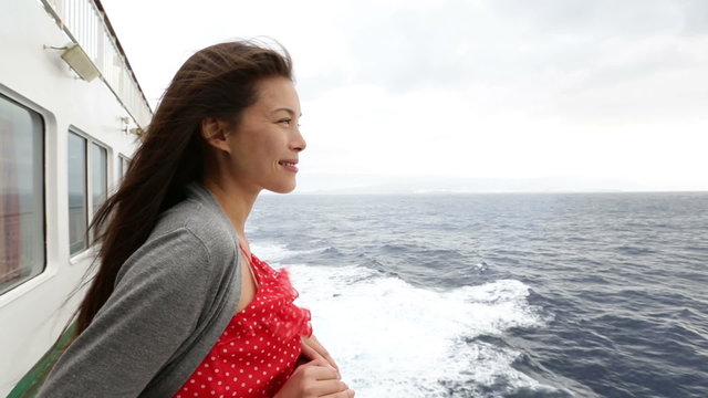 Cruise ship woman on boat in happy smiling looking looking away at sea. Young woman traveling on vacation travel sailing on open sea ocean. Young mixed race Asian Caucasian woman.