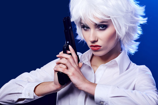 beautiful sexy girl holding gun . blue background