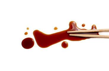 splashes of soy sauce and chopsticks isolated on white. wooden chopsticks dipped in soy sauce spilled. splashes and drops of isolated on white background. flat lay, top view