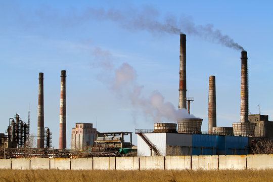Yellow steppe and factory with smoking chimneys against the blue