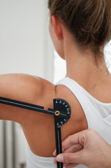Physiotherapist measuring shoulder flexion with goniometer - obrazy, fototapety, plakaty