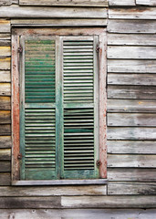 Old rustic vintage dilapidated antique house home building structure with green window shutters closed