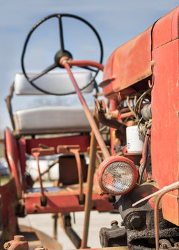 Old vintage antique red farm working tractor outside in the sun on a clear day 