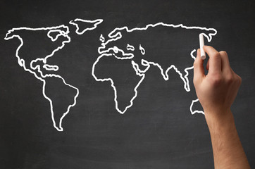 Adult drawing world map on chalkboard