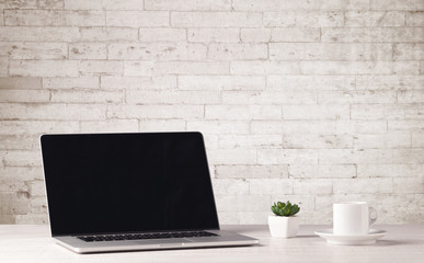 Business laptop with white brick wall