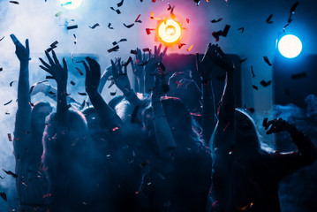 party at a nightclub, young people boys and girls dancing in smoke and confetti