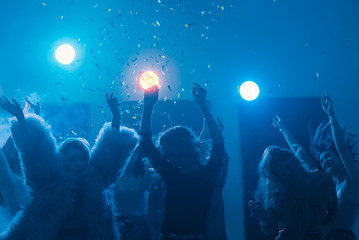 party at a nightclub, young people boys and girls dancing in smoke and confetti