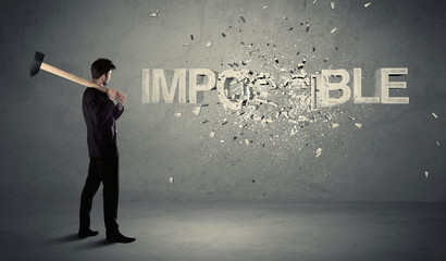 Business man hitting impossible sign with hammer