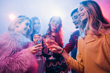 Young friendly people toasting in night club