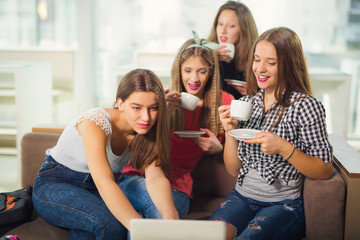 Portrait of four young women sitting at the table in the cafe