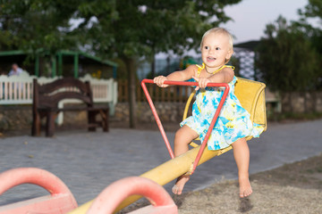 The child, a little girl goes for a drive on a swing in the playground, summer vacation, carefree childhood, education and children's activities